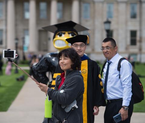 Graduate and family taking photo with Herky