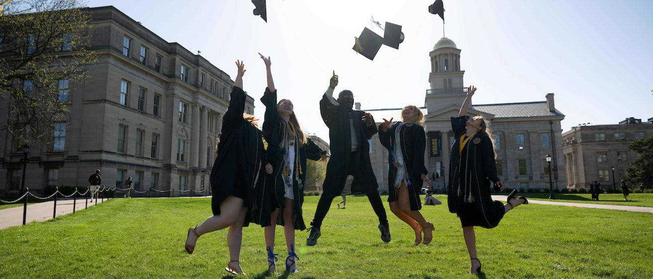 Graduates jumping and throwing caps on Pentacrest